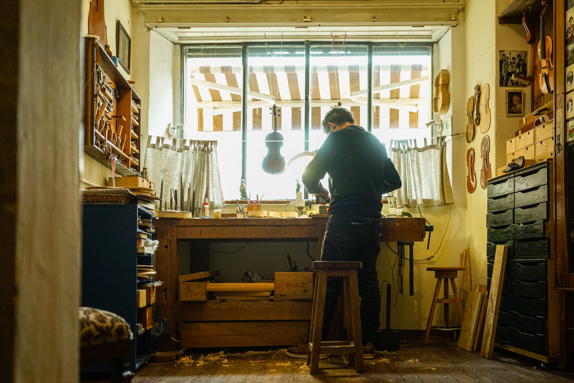 A craftsperson at work in a small Lisbon atelier, back to the camera, focused on the bench.